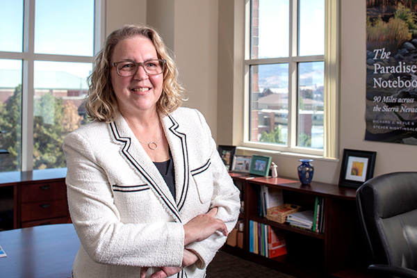 Dean Catherine Cardwell standing in front of a desk, in a relaxed position with her arms crossed.