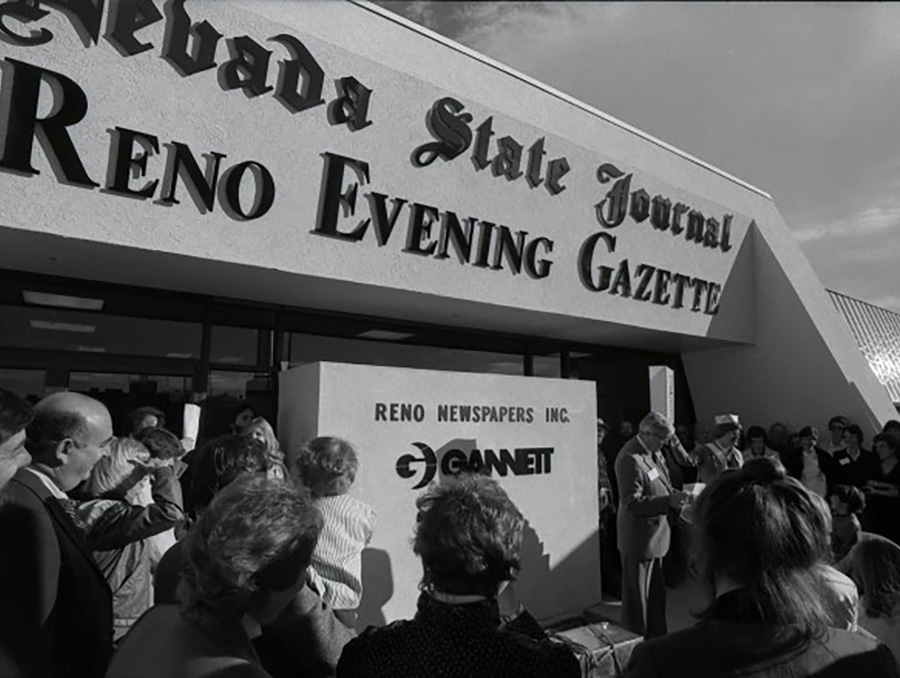 A crowd of people stand outside of the Reno Gazette Journal Building looking on as a commemorative time capsule is preserved during a ceremony.