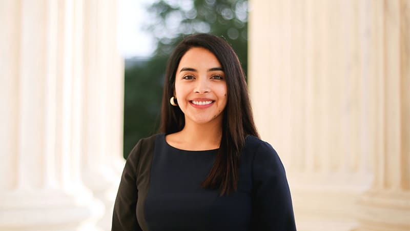 Maritza Perez smiles in front of a government building.