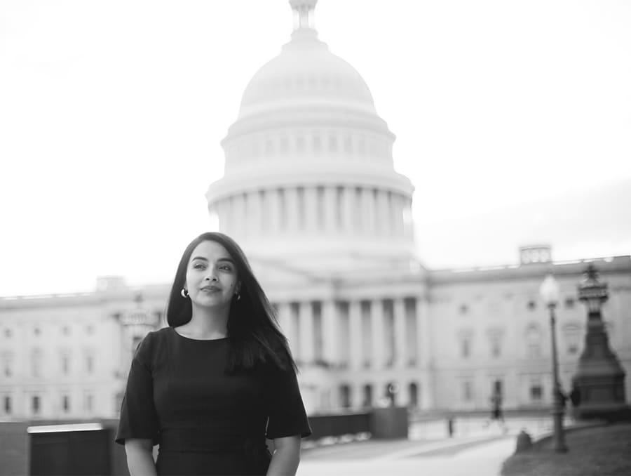 A black and white photo of Maritza Perez standing in front of the U.S. Capitol building.