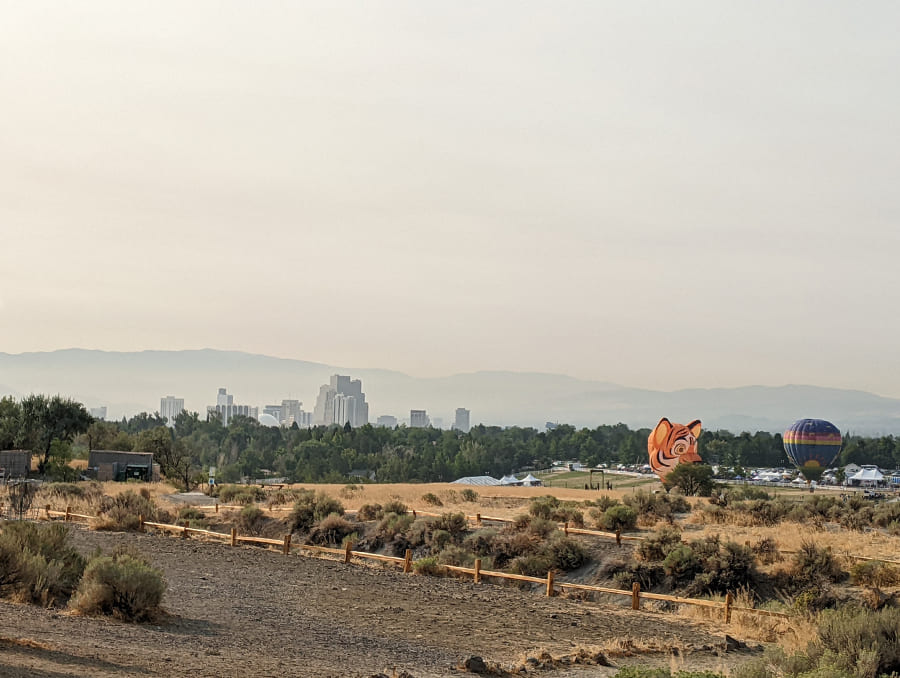 Reno skyline fills with smoke pollution with hot air balloons in the distance. 