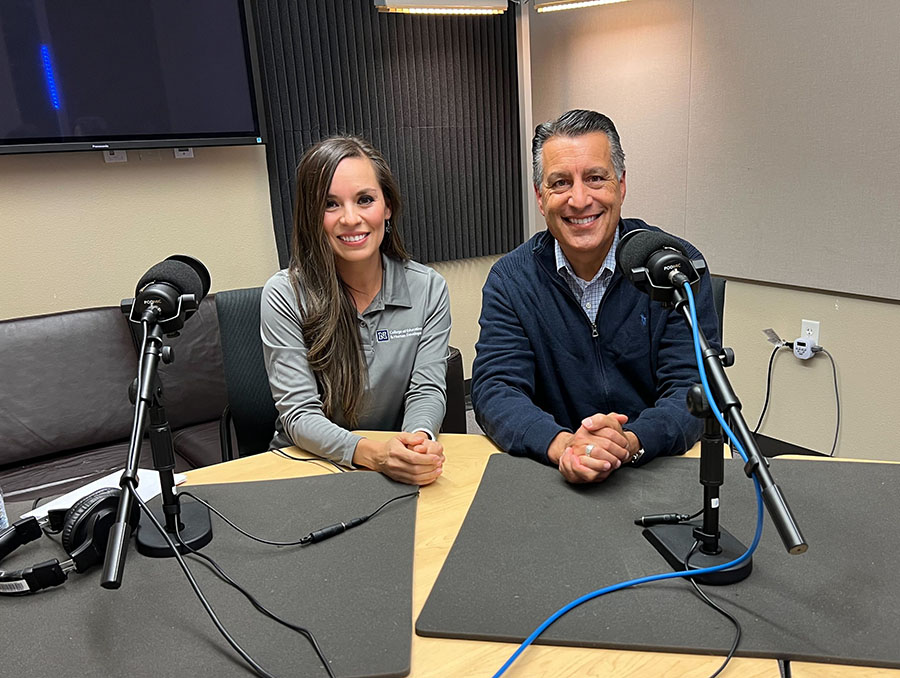 Dr. Jafeth Sanchez and President Brian Sandoval smile while sitting next to each other in the recording space