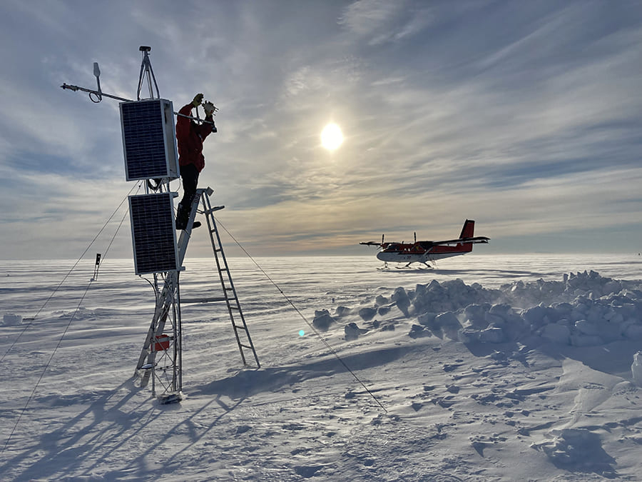 adjusting instruments on tower on Antarctic ice shelf