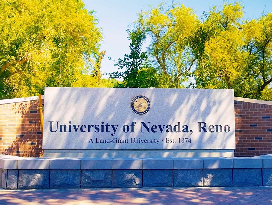 The University of Nevada, Reno monument located outdoors with trees behind it. The monument includes the University's seal as well as lettering that reads, "University of Nevada, Reno. A Land Grant University Est. 1874
