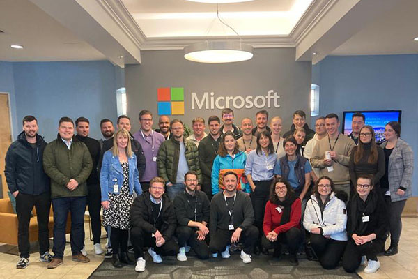 Group of students and faculty gather in front of Microsoft logo