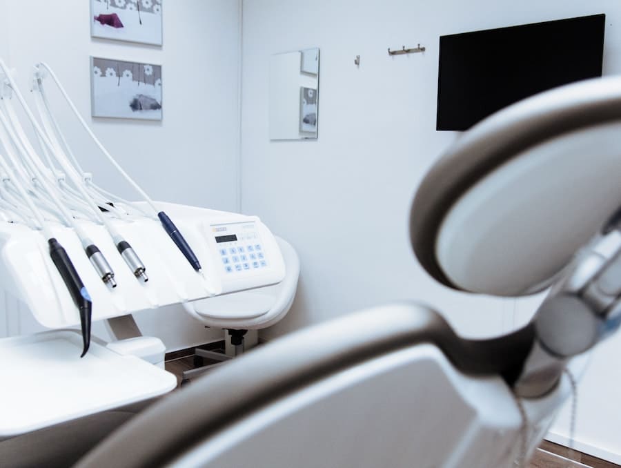 Doctor's office with a patient chair and various tools and instruments on a white desk.