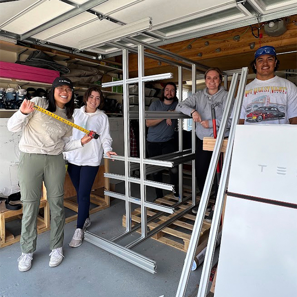 Five students inside a residential garage around metal scaffolding