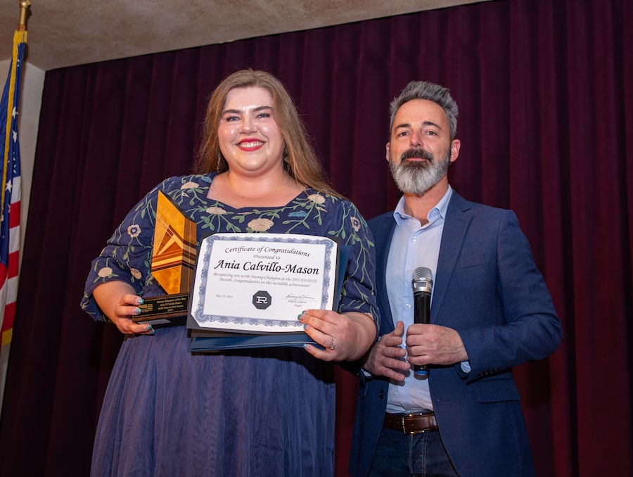 Ania Calvillo-Mason smiling with an award and posing with an award announcer at the NCET ceremony