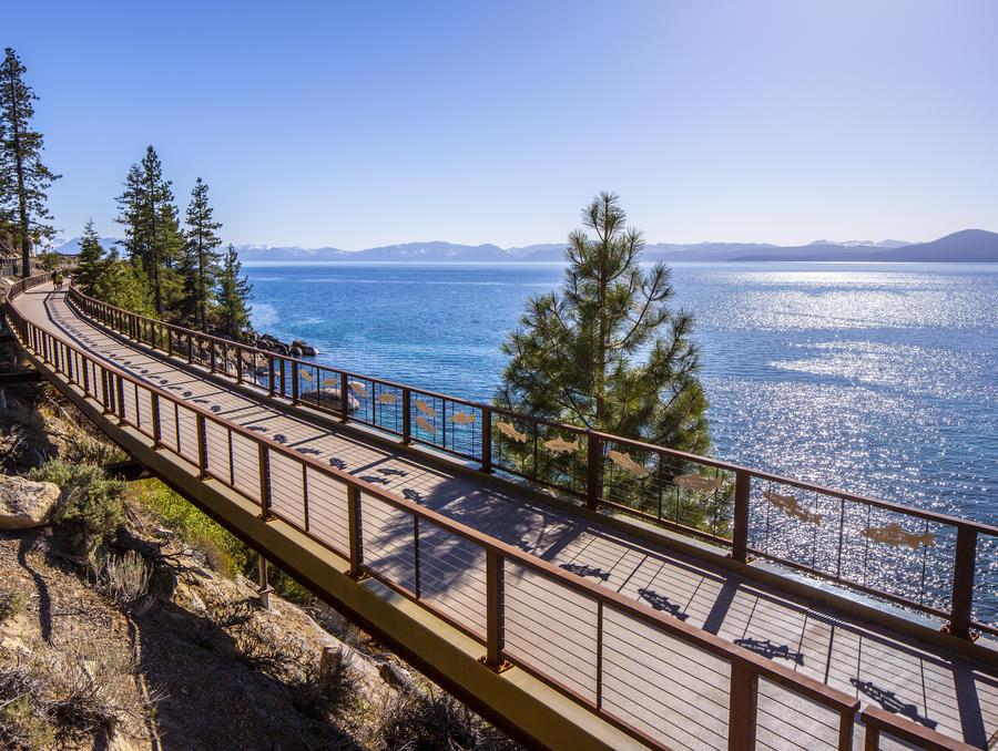 View of a walk way with railings in front of Lake Tahoe in a sunny day.