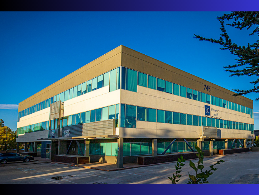 The outside of the University Health building with a clear blue sky behind it.