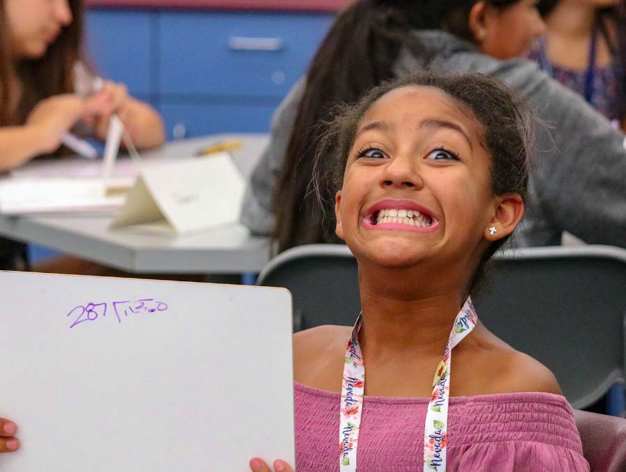 A girl holding up a math problem