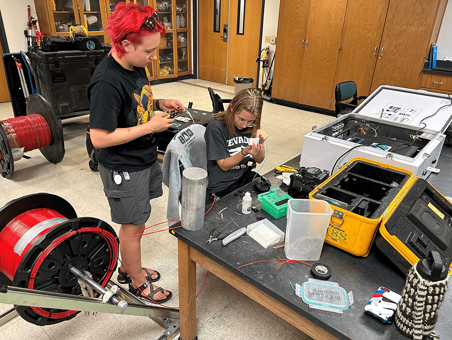 Sophomore Odezsa Gautschi (left) and graduate student and University alumna (2023) Kayleigh Dohm splice fiber optic cable. 