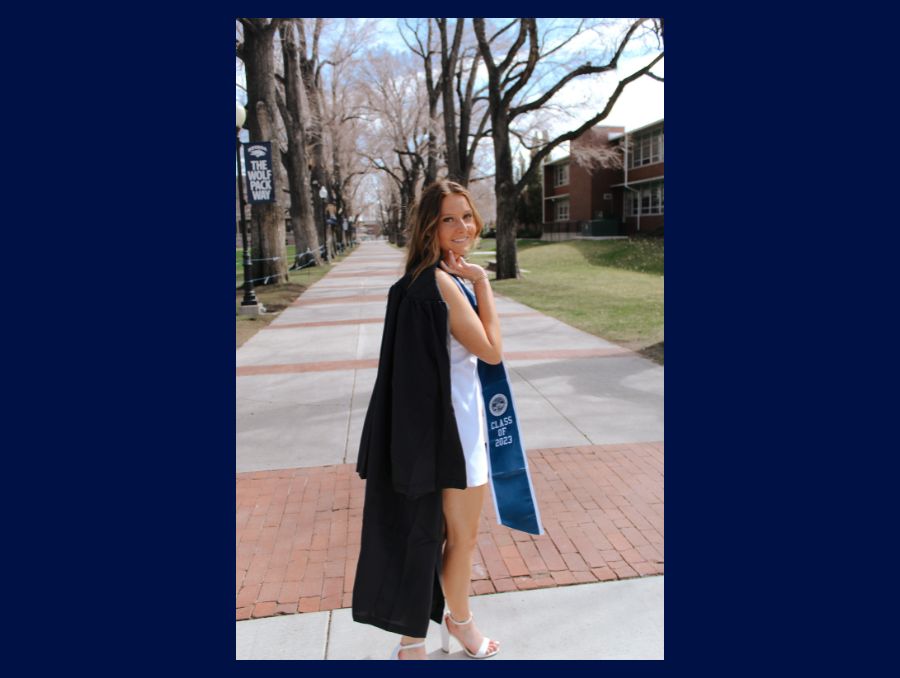 Jessica stands in the quad with her graduation gown over her shoulder