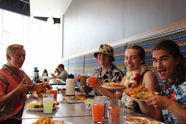 A group of about five students eating and smiling while eating at Pack Place on campus.