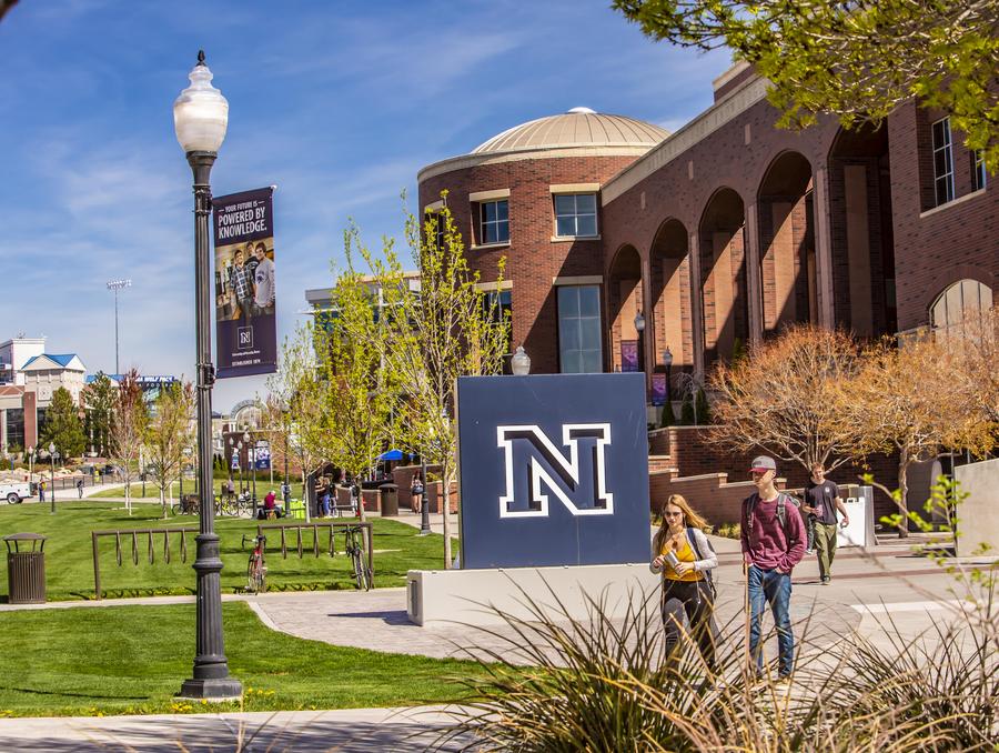 Students walking in front of University of Nevada, Reno N logo in front of the Mathewson-IGT Knowledge Center