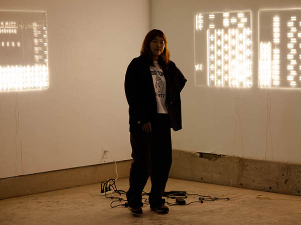 Choey poses in front of her artwork in the "Secret Echo" exhibit space.