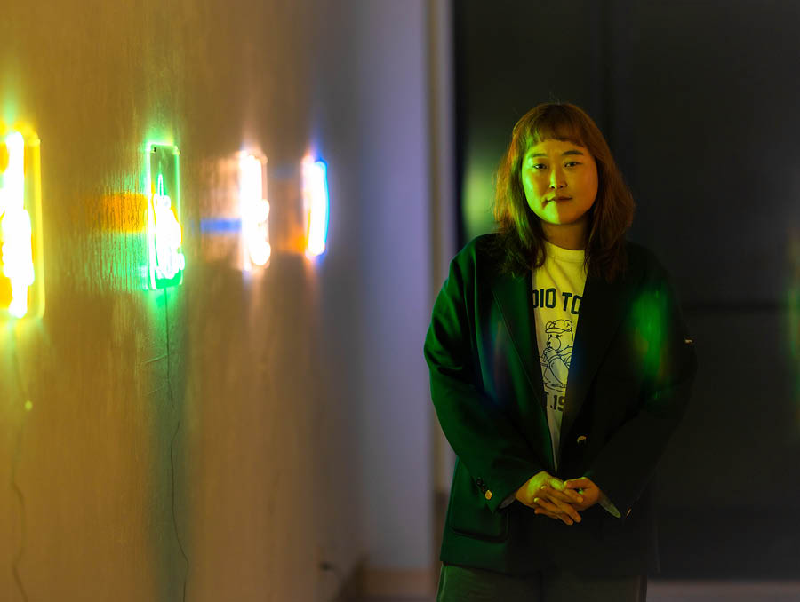 Artist Choey Eun Young Cho standing by her neon light art in the exhibit "Secret Echo"