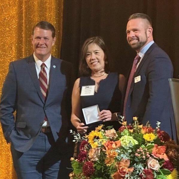 Grace Chou receives EDAWN coin, pictured with Taylor Adams and Doug Erwin