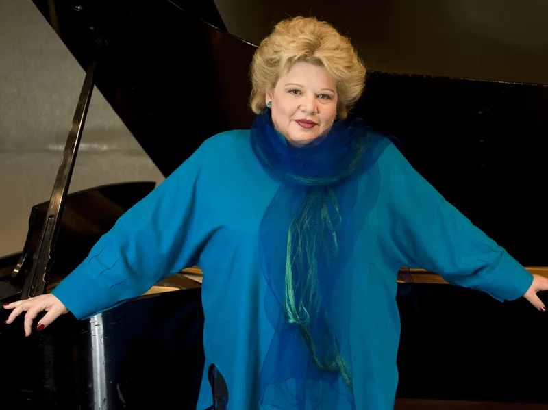 Dolora Zajick posing in front of a grand piano.