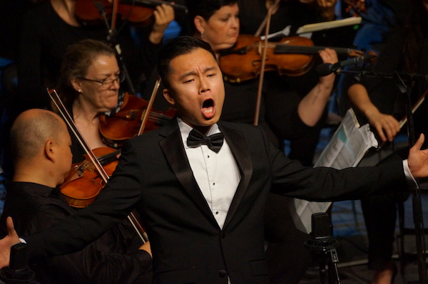 Michael TK Lam performing on stage in a tuxeudo.