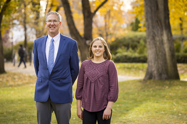 Keith Dennett and Brigida Rovarino stand outside on the quad, smiling..