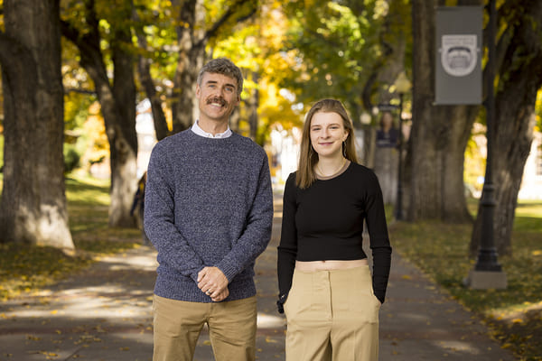 Bret and Caitlin stand outside on the quad, smiling.