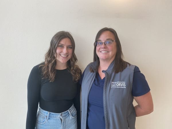 Eva Burgeson and Shannon Richard smile in front of a wall. 