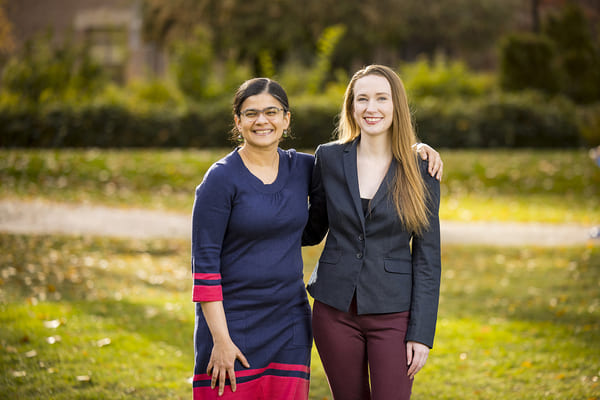 Paromita Pain and Haley Ekberg stand outside on the quad, smiling.