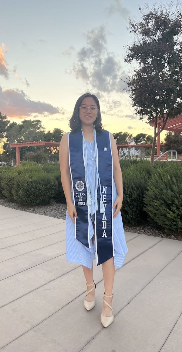 Ja Ja Chang outside on the quad wearing a commencement sash.