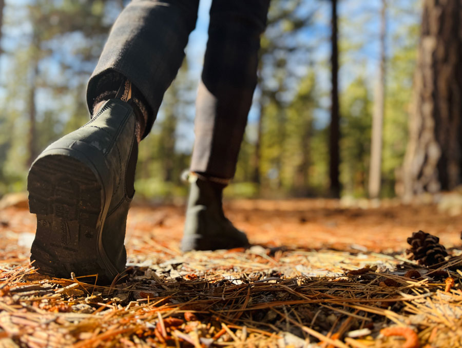 Close up of person's boots hiking through a forest