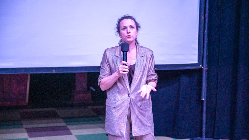 Professor Kari Barber addressing the audience holding a microphone.