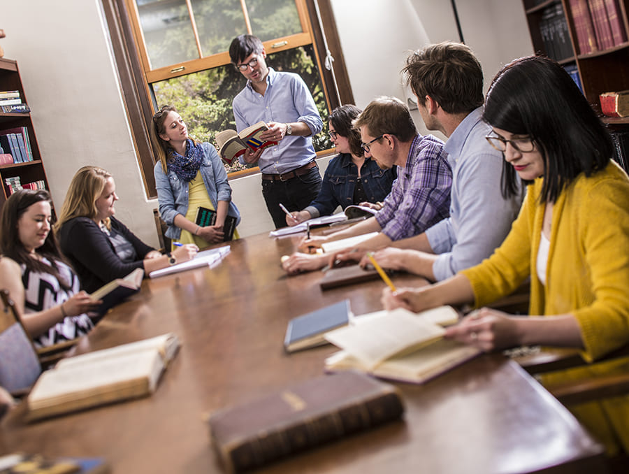 Students at a table reading and writing.