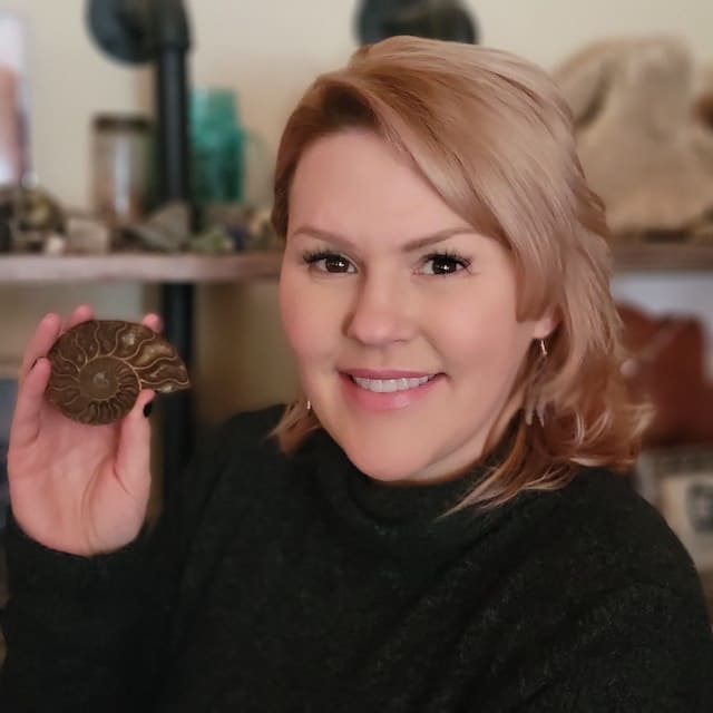 Woman smiling holding a brown seashell.