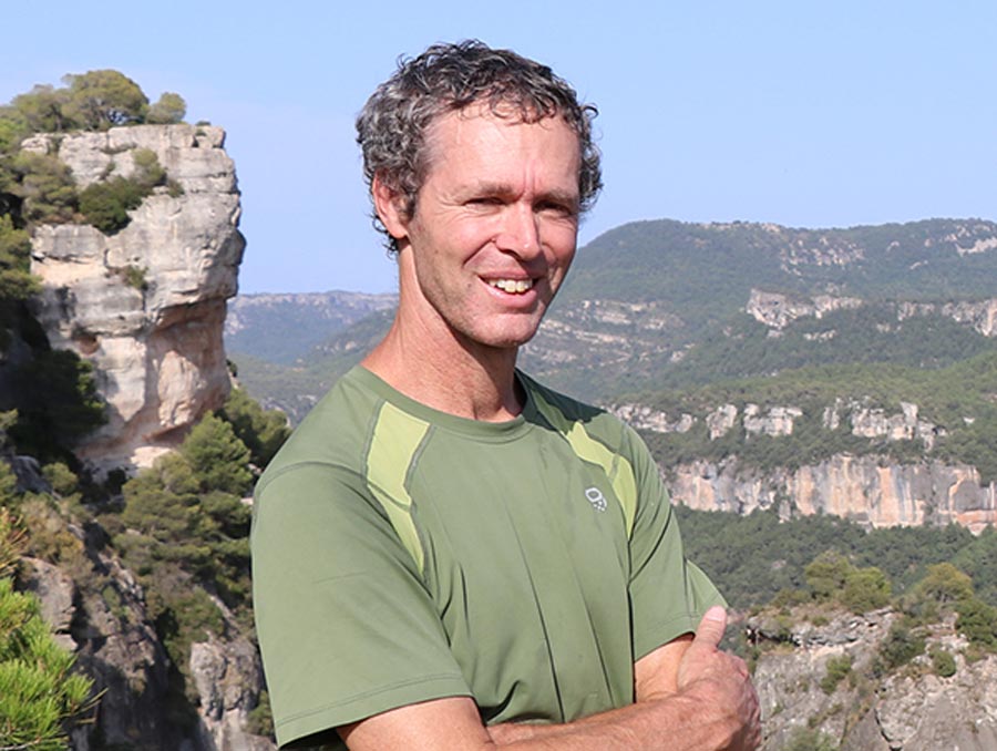 Lee Dyer smiles on top of a mountain.