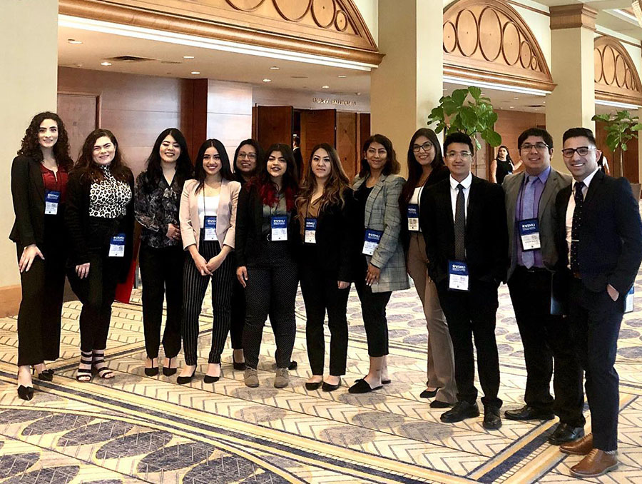 Students and faculty pose in a the hall of a conference center. 