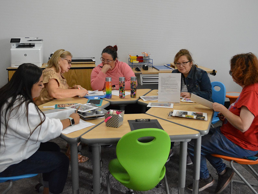 A group of child care educators sitting at a table planning out professional portfolio assignments.