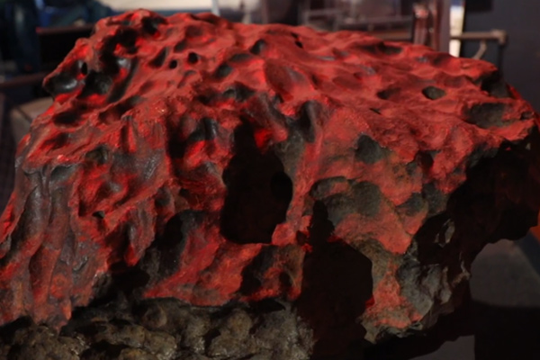 A gray lumpy rock with a red light shining on it.