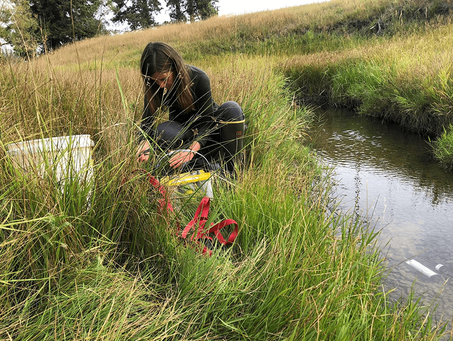 Joanna Blaszczak sitting by a stream of water installing sensors.