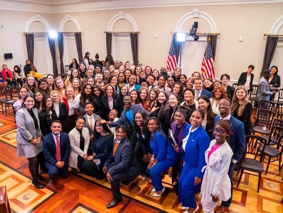 Group of people in business clothes centered in the room standing closely together.