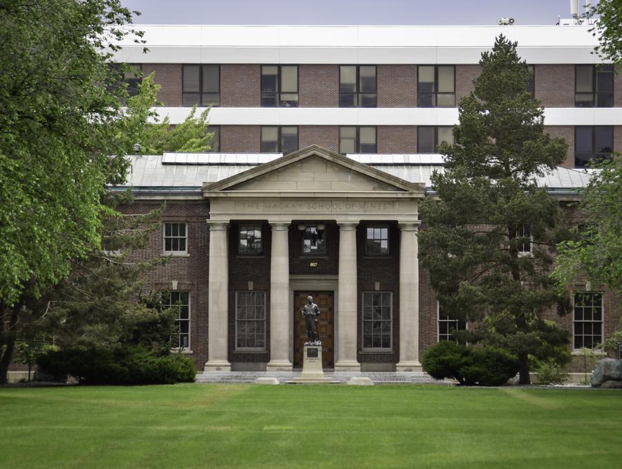 The University's quad as it faces the Mackay statue. Green grass and trees line the foreground.