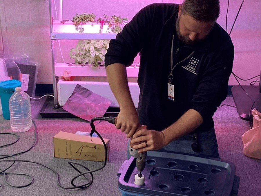 An instructor teaching students how to make a hydroponic unit.