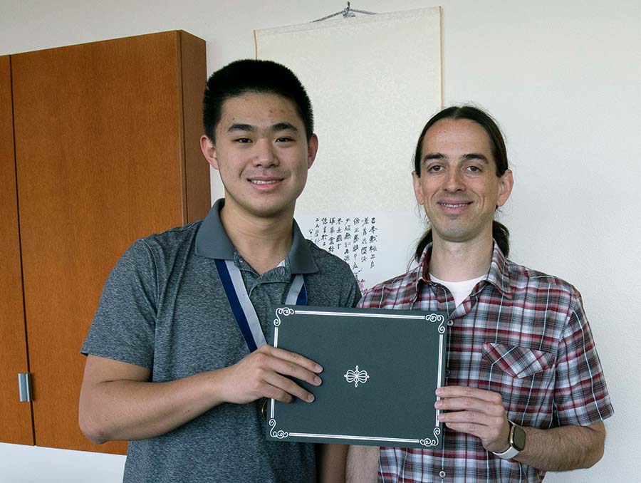 Jimson Huang and Paul Hurtado, an associate professor of math, both holding a single certificate cover.
