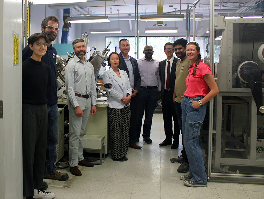 Nine people standing in a lab and looking at the camera.