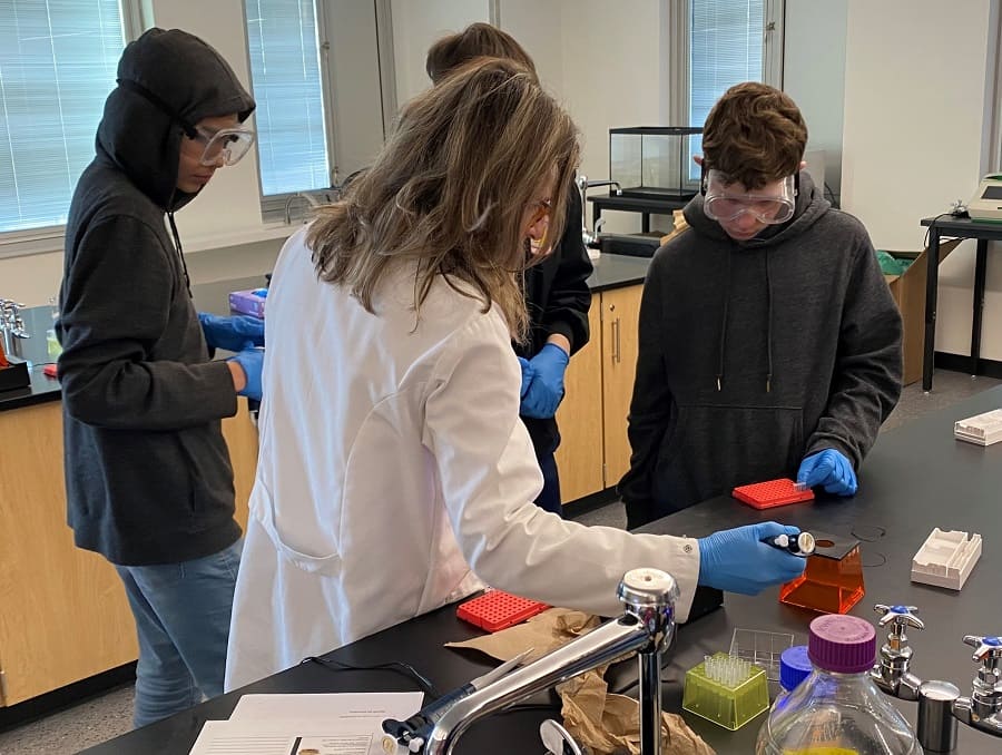 Professor Patricia Santos works with Hug High School students on lab experiments.