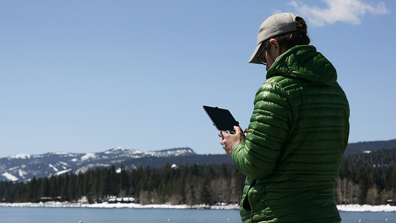 Person flying a drone from the shore of Lake Tahoe