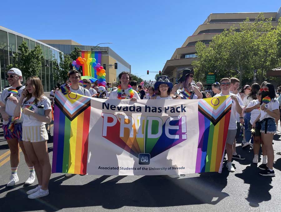Students hold a banner that reads, "Nevada has Pack PRIDE!" at the annual Pride parade in downtown Reno. Many people are dressed in rainbow UNR t-shirts.
