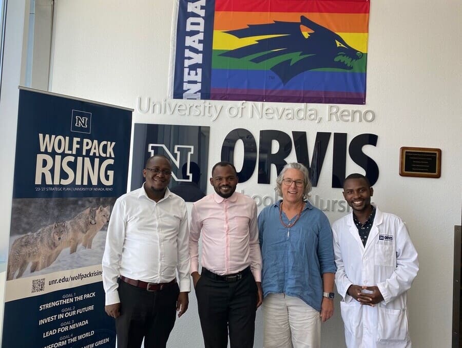 Principal of the Uganda Nursing School Bwindi, Robert Kamugisha, Principal of the Uganda College of Health Sciences Bwindi, Onesmus Keizire, Associate Professor at Orvis School of Nursing, Deborah Lowell Shindell, Tutor and Deputy Registrar at the Uganda Nursing School, Bwindi Andrew Ansinguza in front of the Orvis School of Nursing sign