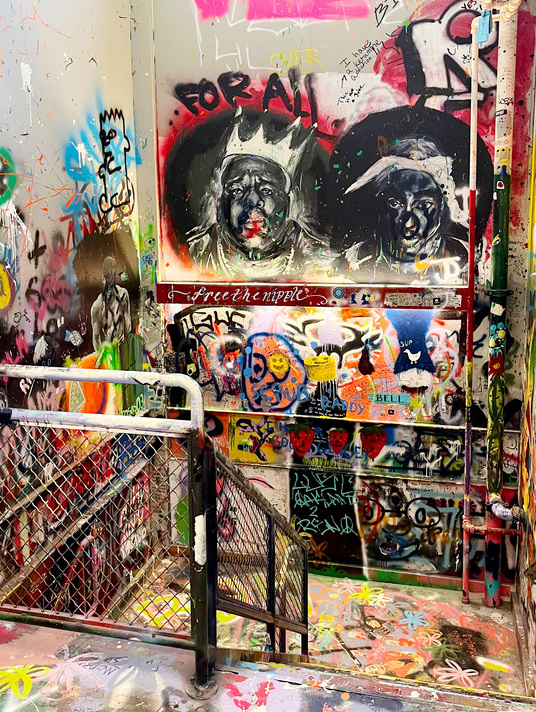 Artist stairwell in Church Fine Arts building depicting with spray painted faces and words.