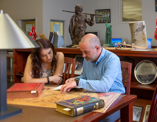 Inaki seated at a table with a student in the Basque Library reading room.