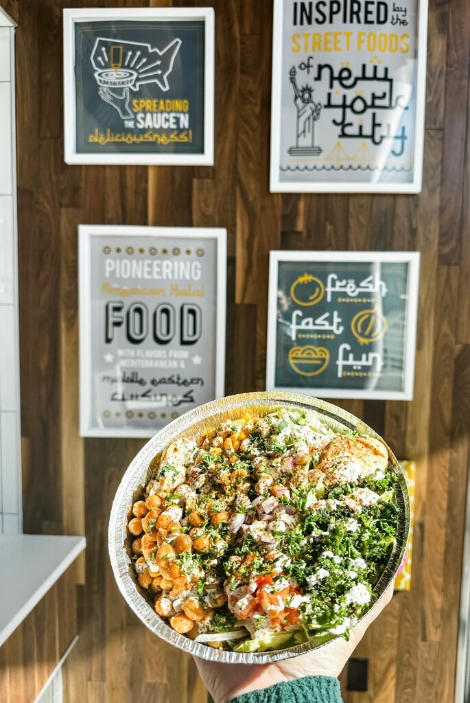 A bowl of food with chicken, chickpeas, and salad.